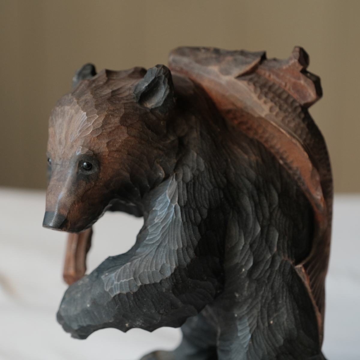 古いガラス目のシャケを持ち帰る木彫りの擬人熊